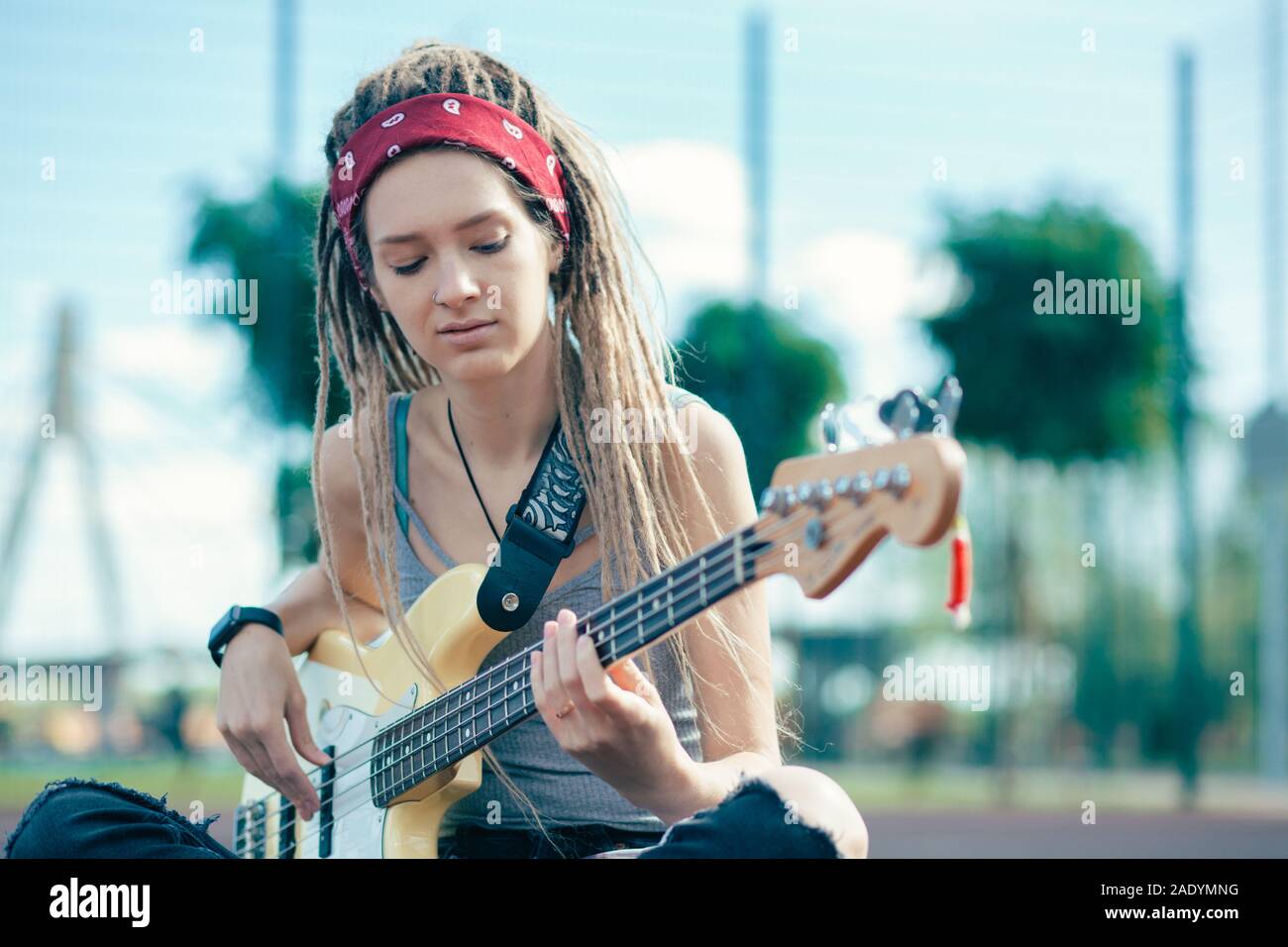 Nachdenkliche junge Dame alleine sitzen und Gitarre spielen Stockfoto