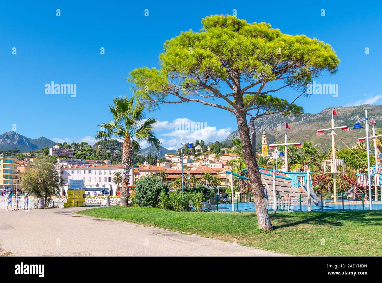 Touristen und Einheimische genießen einen sonnigen Tag an der französischen Riviera, während sie sich am Meer im Fossan Beach Park in Menton, Frankreich, entspannen. Stockfoto