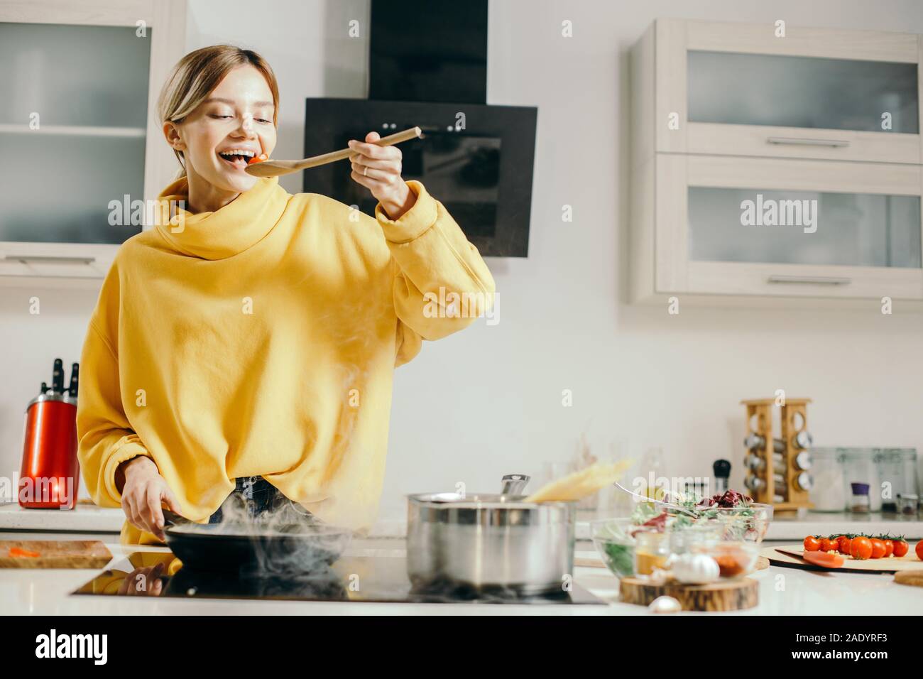 Happy lady tasting Cherry Tomaten aus dem Löffel aus Holz Stockfoto