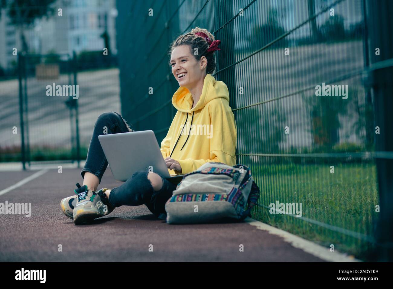 Glückliche junge Frau lachend, während allein mit Ihrem Laptop Stockfoto
