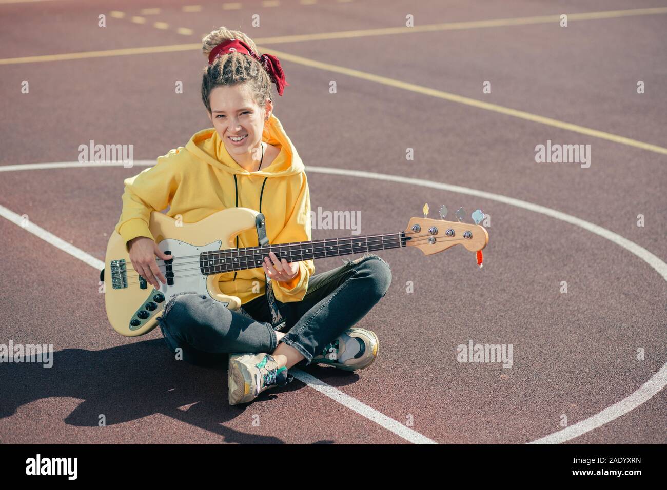Freundliche junge Dame lächelnd zu, die Sie beim Spielen der Gitarre Stockfoto