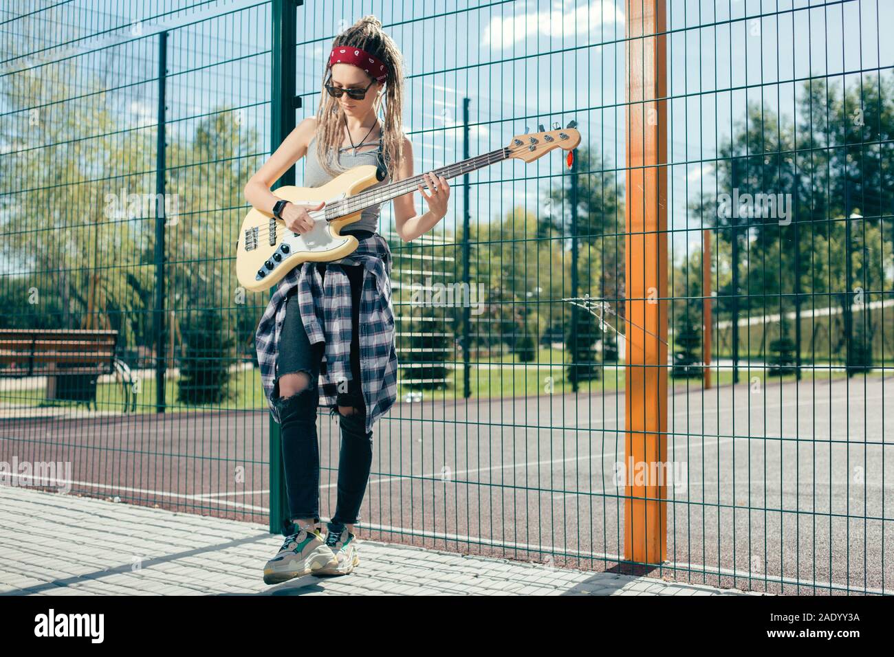 Talentierte junge Dame an, Gitarre zu spielen, während Sie auf dem Sportplatz Stockfoto