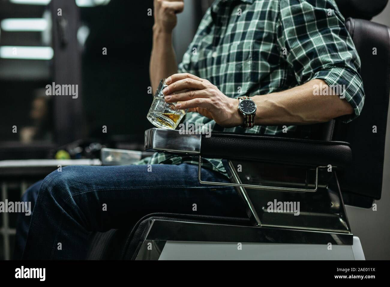 Mann in kariertem Hemd sitzen und halten Glas Whiskey Stockfoto