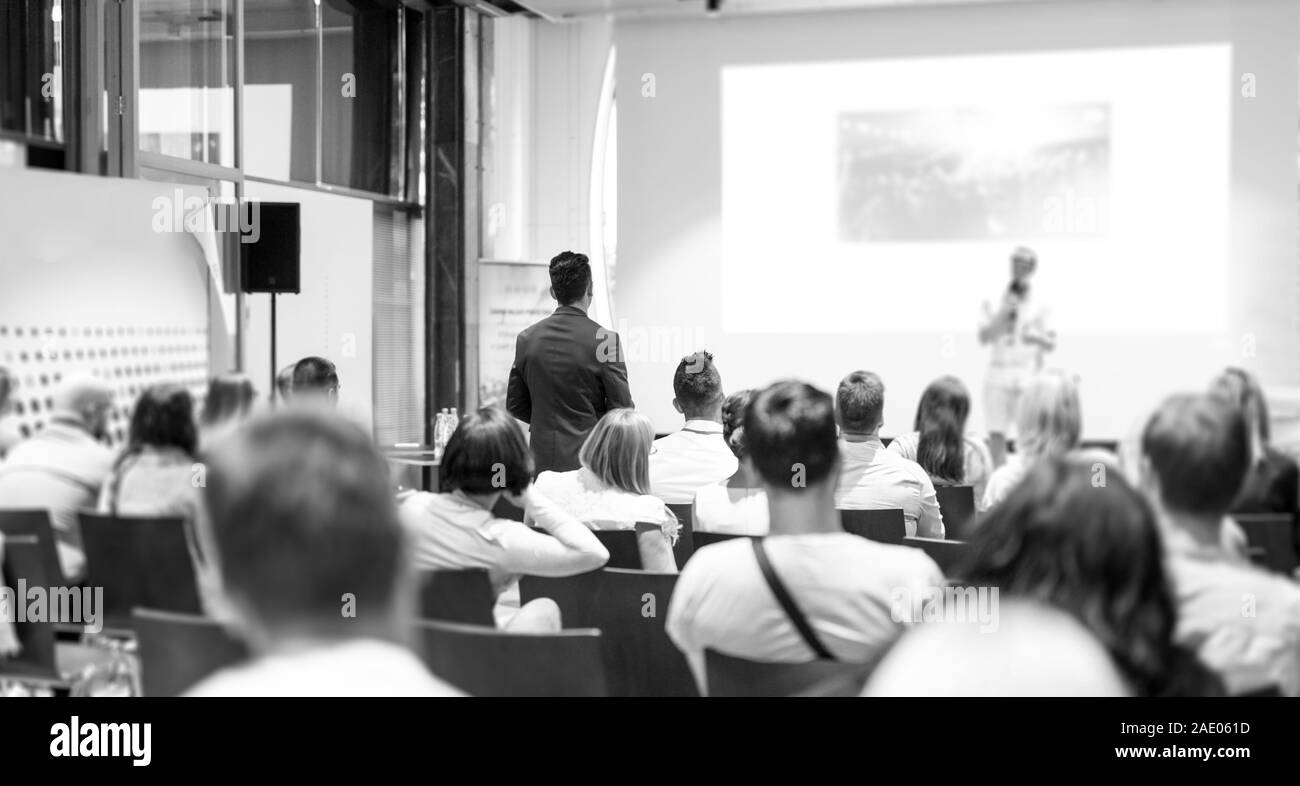 Unternehmer im Publikum stehen und Fragen stellen bei Business Konferenz zu speeker. Stockfoto