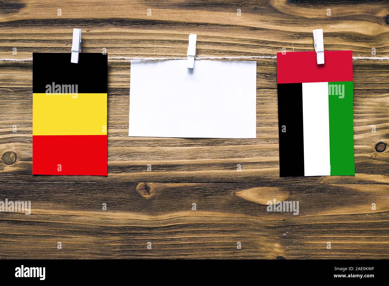 Hängenden Flaggen Belgien und den Vereinigten Arabischen Emiraten zu Seil mit wäscheklammer mit Kopie Raum befestigt auf weißem Papier auf Holz- Hintergrund. Diplomat Stockfoto
