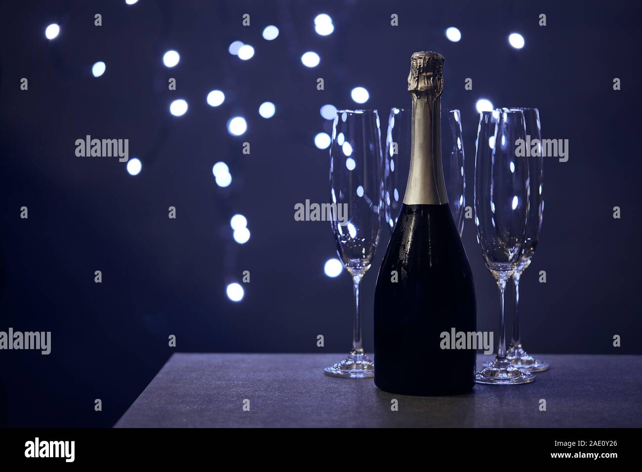 Flasche Champagner und Gläsern mit unscharfen Weihnachtsbeleuchtung Stockfoto