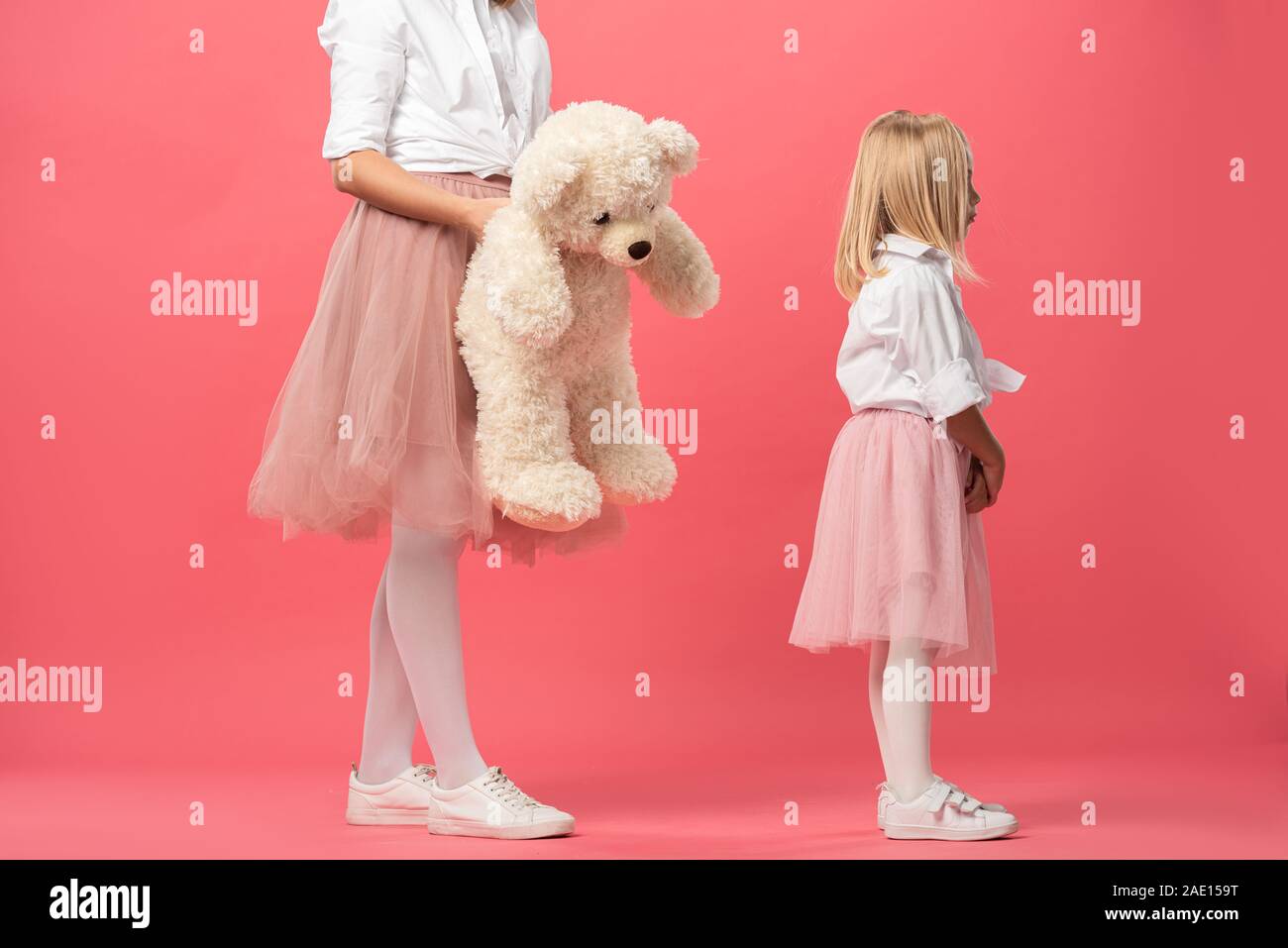 7/8-Ansicht von Mutter und Teddybären zu beleidigt Tochter auf rosa Hintergrund Stockfoto