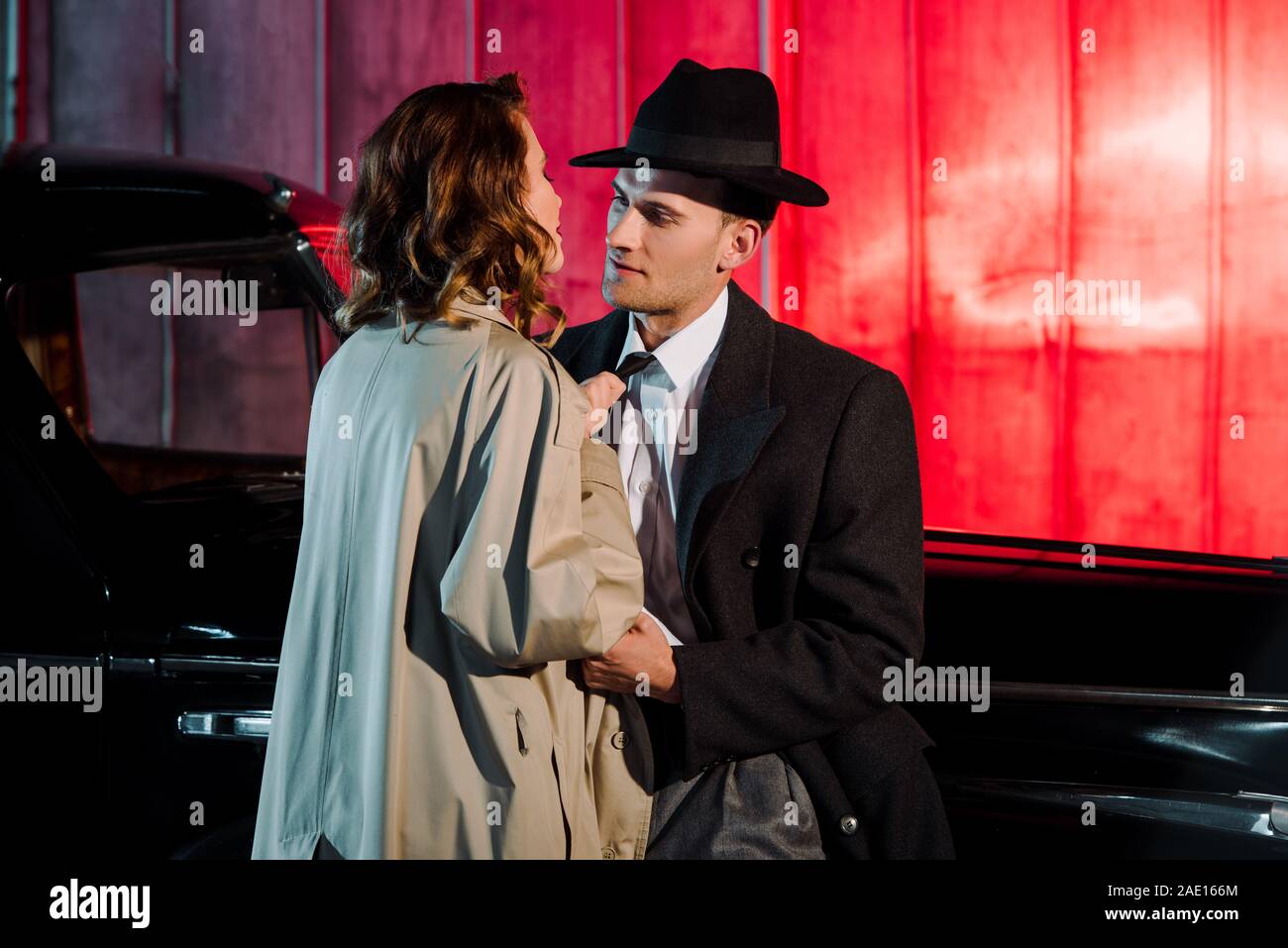 Stattliche Gangster in hat bei der Frau in der Nähe von Oldtimer suchen Stockfoto