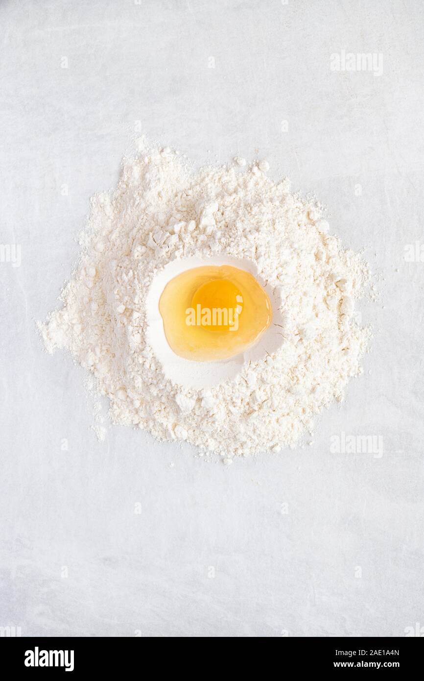 Rohes Ei in Mehl auf einer weißen Fliese Hintergrund. Backzutaten Stockfoto