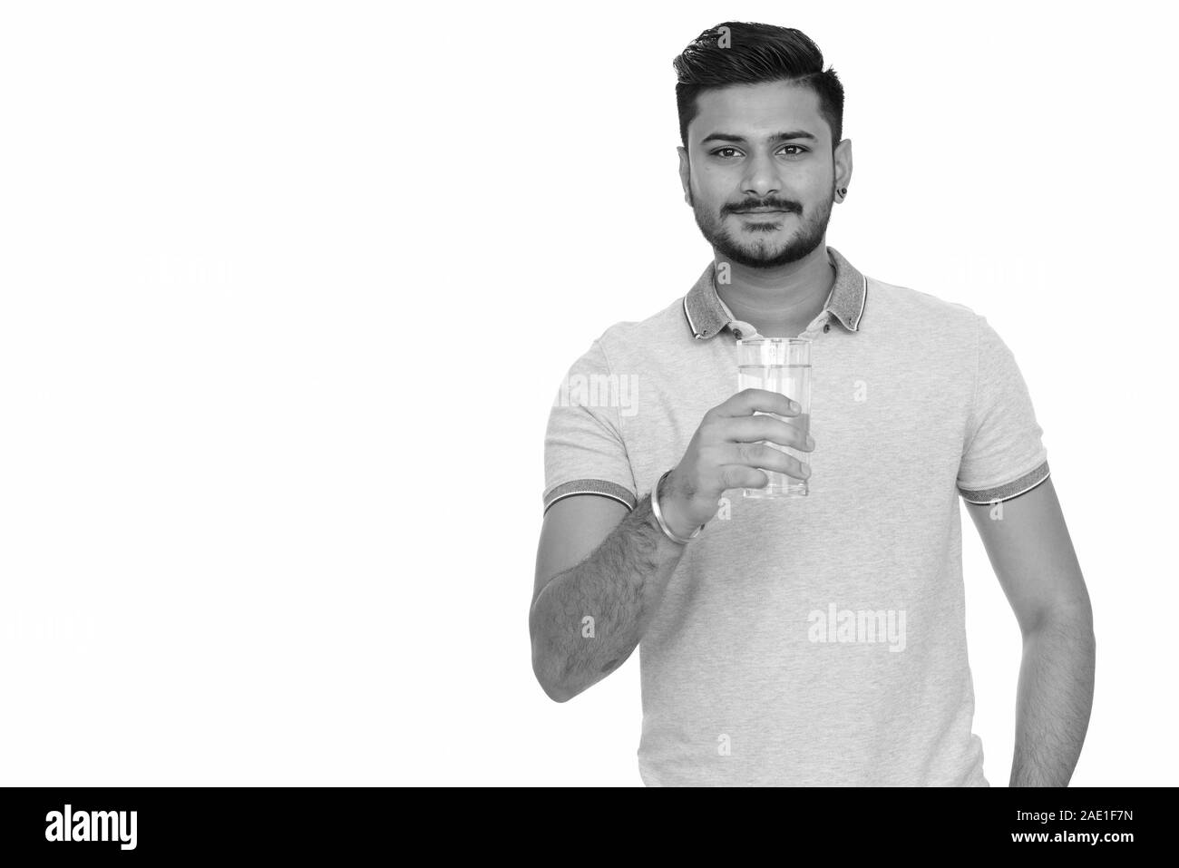 Junge schöne Indische Mann hält Glas Wasser Stockfoto