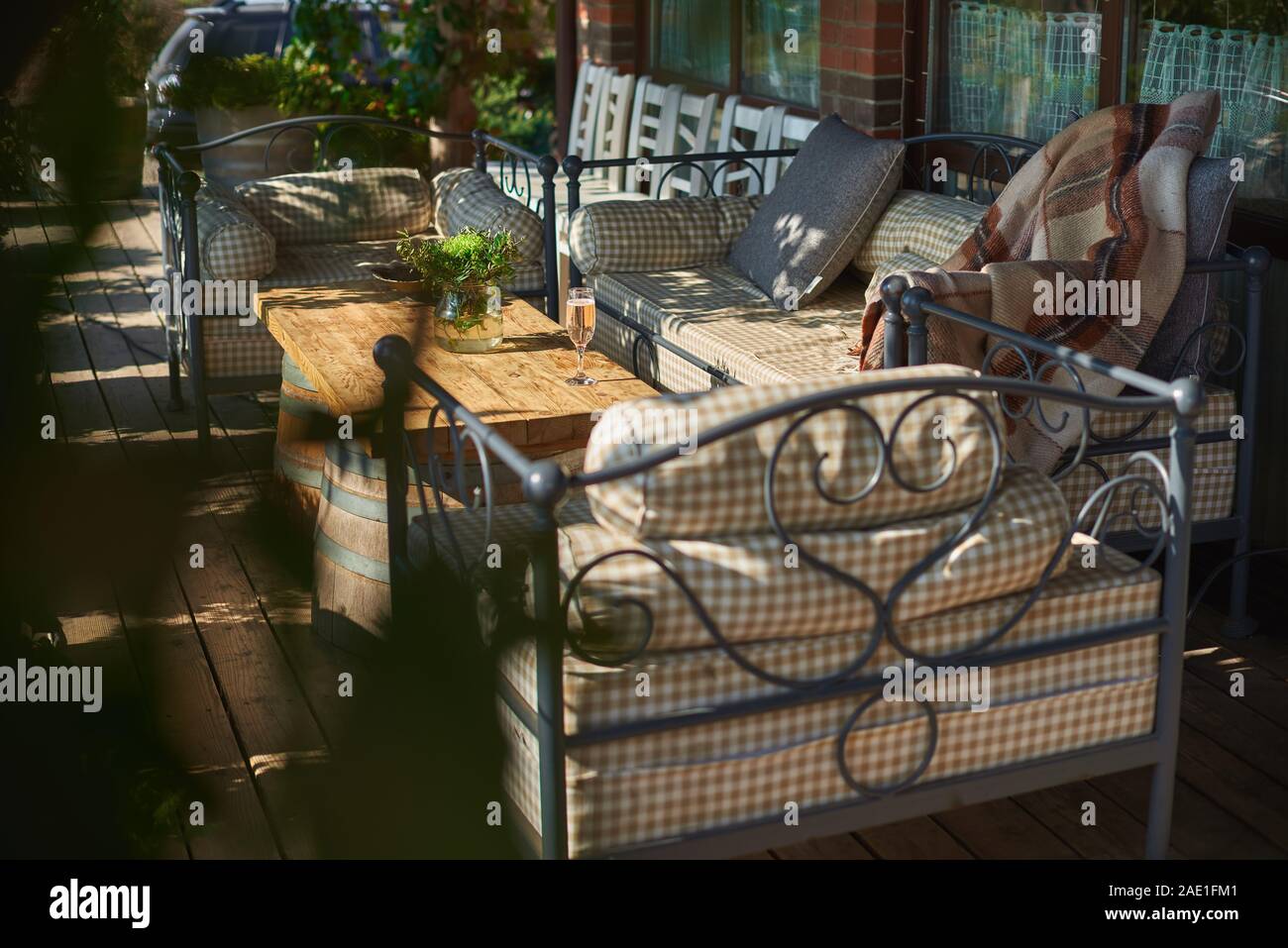 Gemütliche Terrasse mit Sofas für Rest, Glas mit Champagner auf einer hölzernen Tisch. Sonnigen Tag. Stockfoto