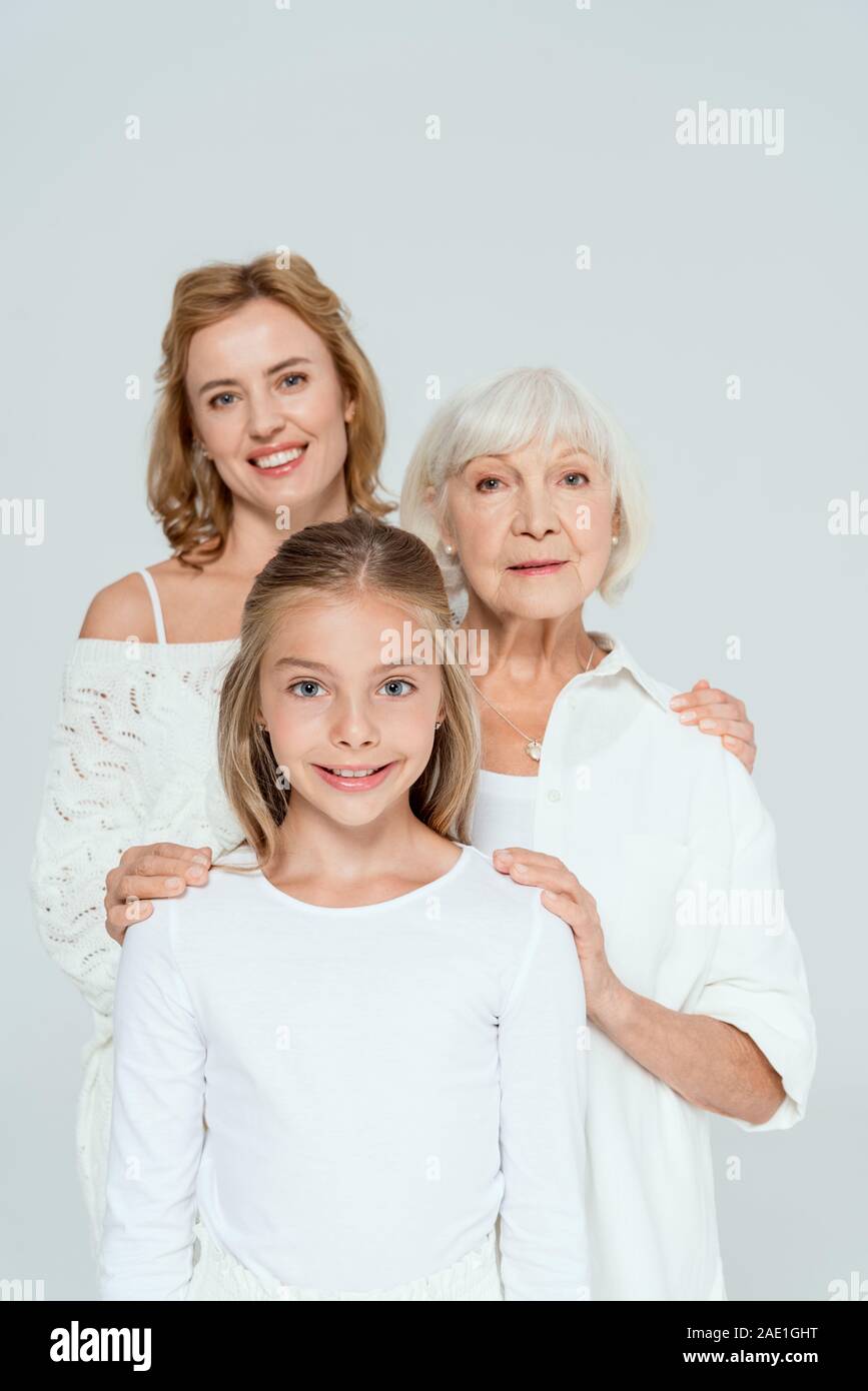 Lächelnde Mutter, Großmutter und Enkelin umarmen isoliert auf Grau Stockfoto