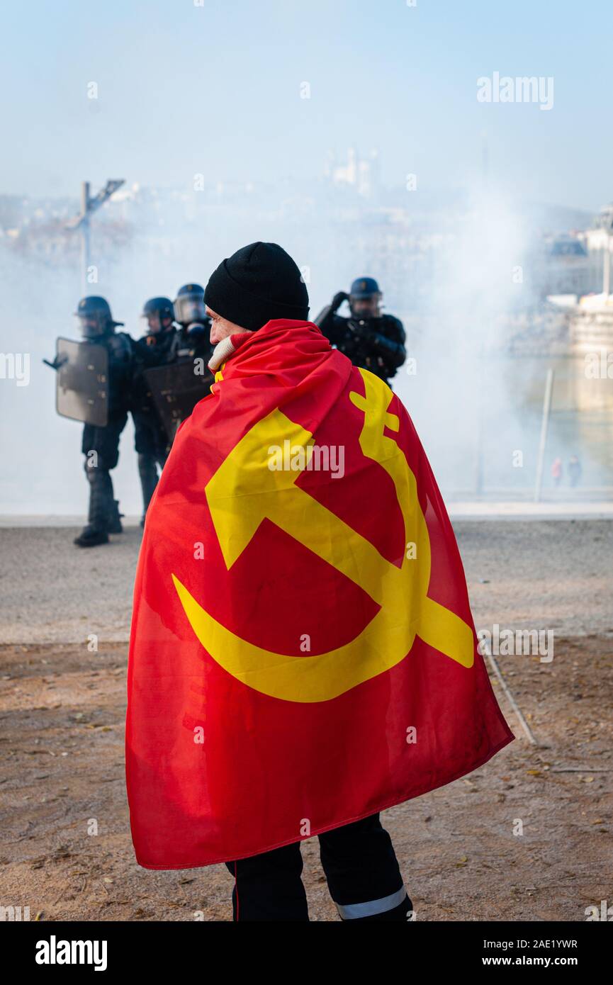 Dezember 05, 2019, Lyon, Auvergne-Rh ône-Alpes, France-Demonstration gegen die Rentenreform. Ein Demonstrator mit einem kommunistischen Flagge auf seinem Rücken in Fr Stockfoto