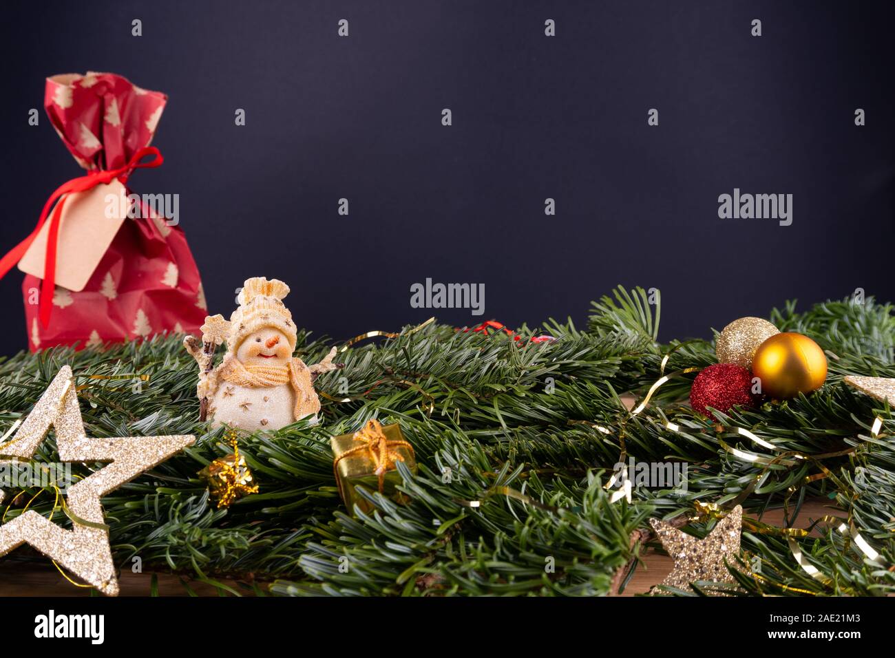 Weihnachtsdekoration (Schneemann, Gegenwart, Sterne, Kugeln) und fir Zweige vor einem schwarzen Hintergrund Stockfoto