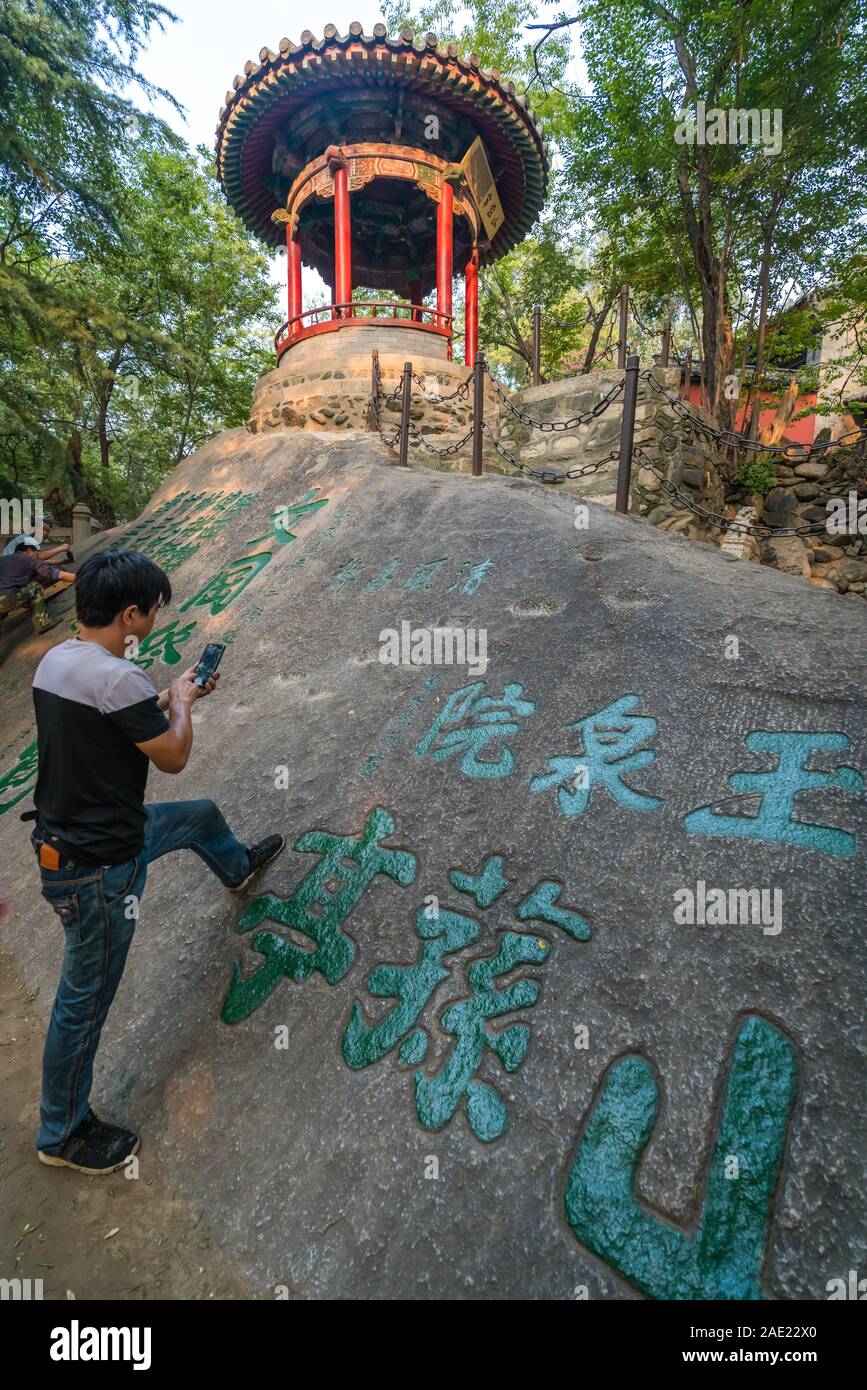 Huashan, China - August 2019: Der Mensch, der seine Arbeit auf einem Smartphone nach dem Lackieren chinesische Kalligraphie Zeichen auf einen Stein in der Stockfoto