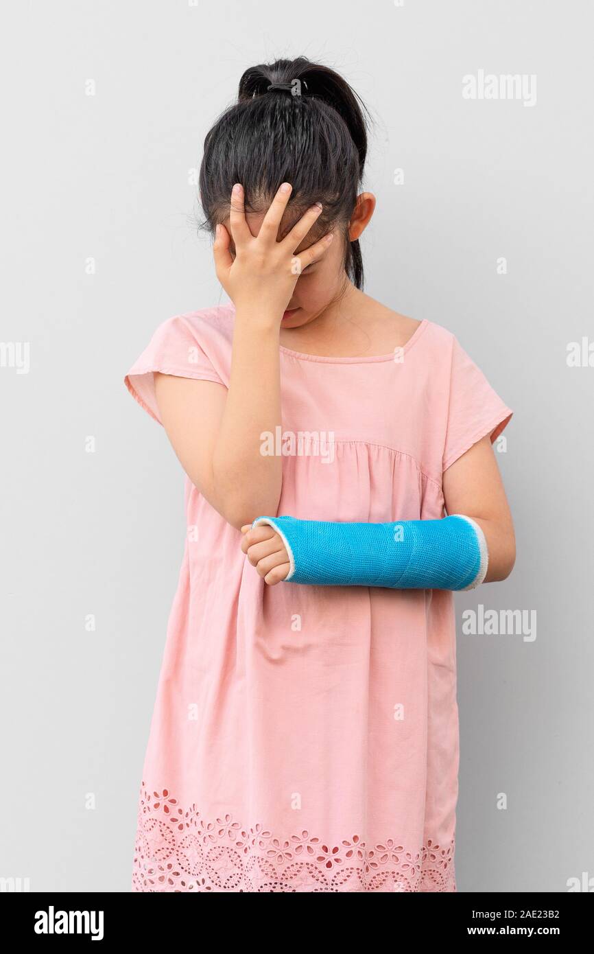 Asiatische Kind mit gebrochenen Arm in mit Verletzen und traurigen Gesichtsausdruck Cast Stockfoto