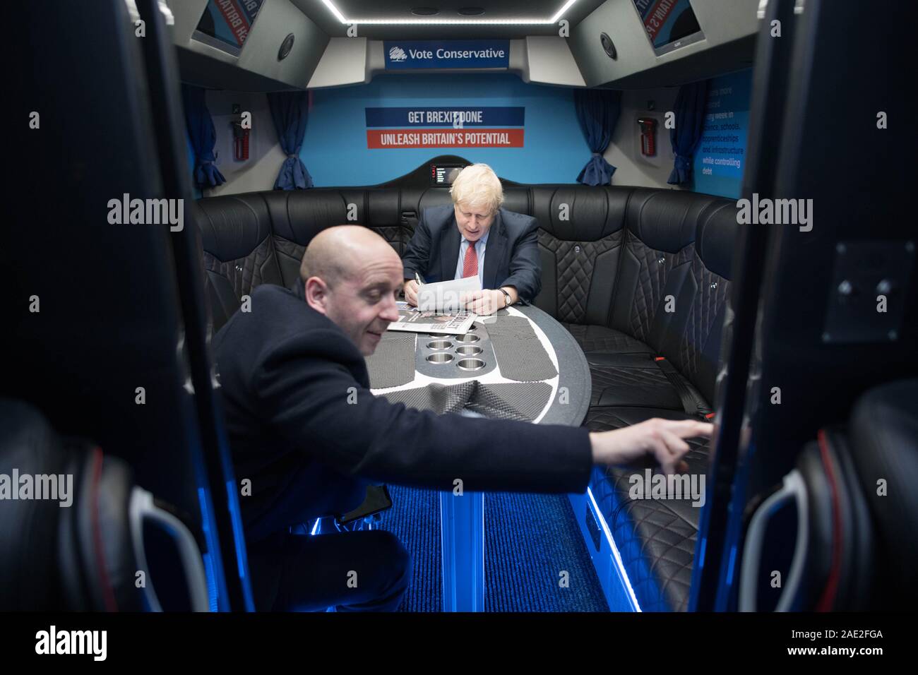 Premierminister Boris Johnson, sitzend mit Seiner Leiterin der Kommunikation, Lee Kain, in seiner Kampagne Bus, wie Sie das Kent Event Center, Maidstone, während auf den Wahlkampf Trail. Stockfoto