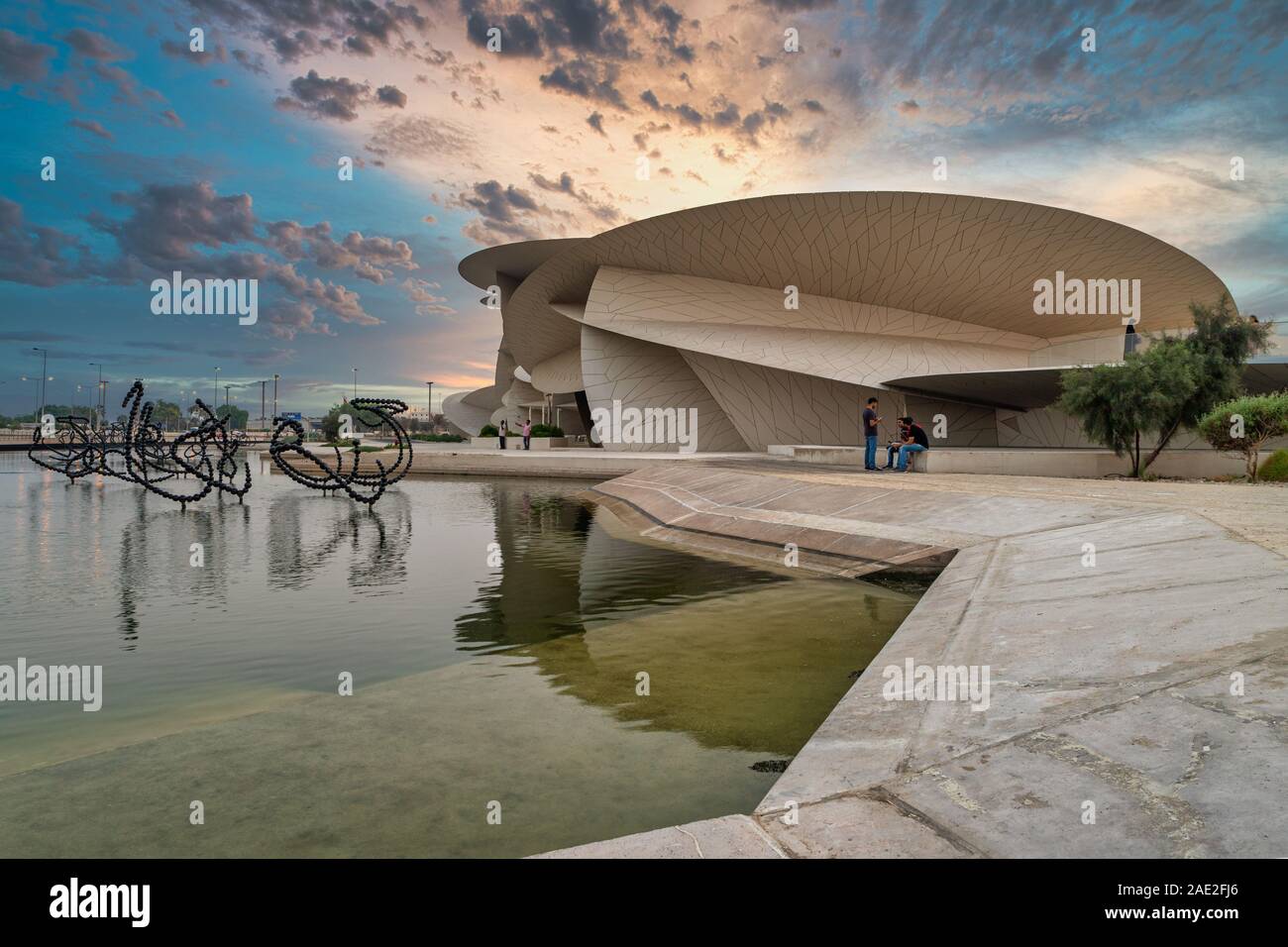 Doha, Katar-Oktober 25,2019 :Nationalmuseum von Katar (Desert Rose) Außenansicht Tageslicht mit Brunnen im Vordergrund und Wolken am Himmel Stockfoto