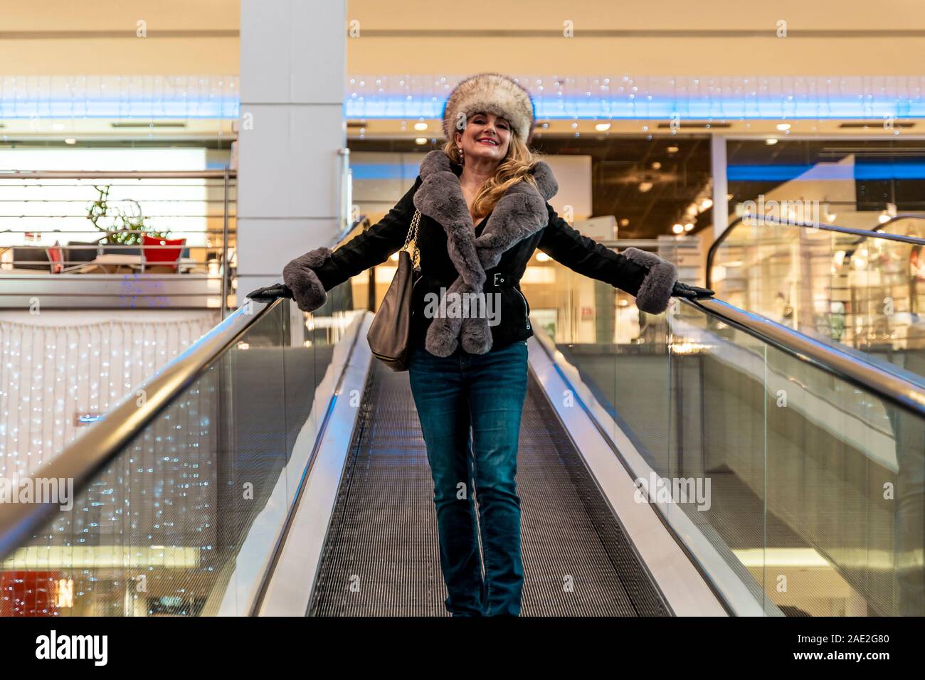 Attraktive Frau geht die Rolltreppen in einem Kaufhaus, während Sie tut Winter Shopping Stockfoto