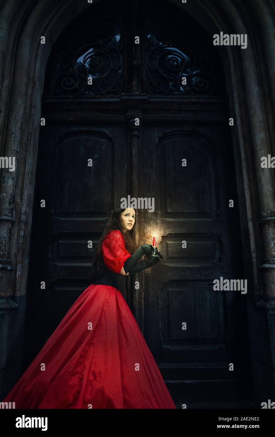 Geheimnisvolle Frau in einem roten Viktorianische Kleid von die alte Tür Stockfoto