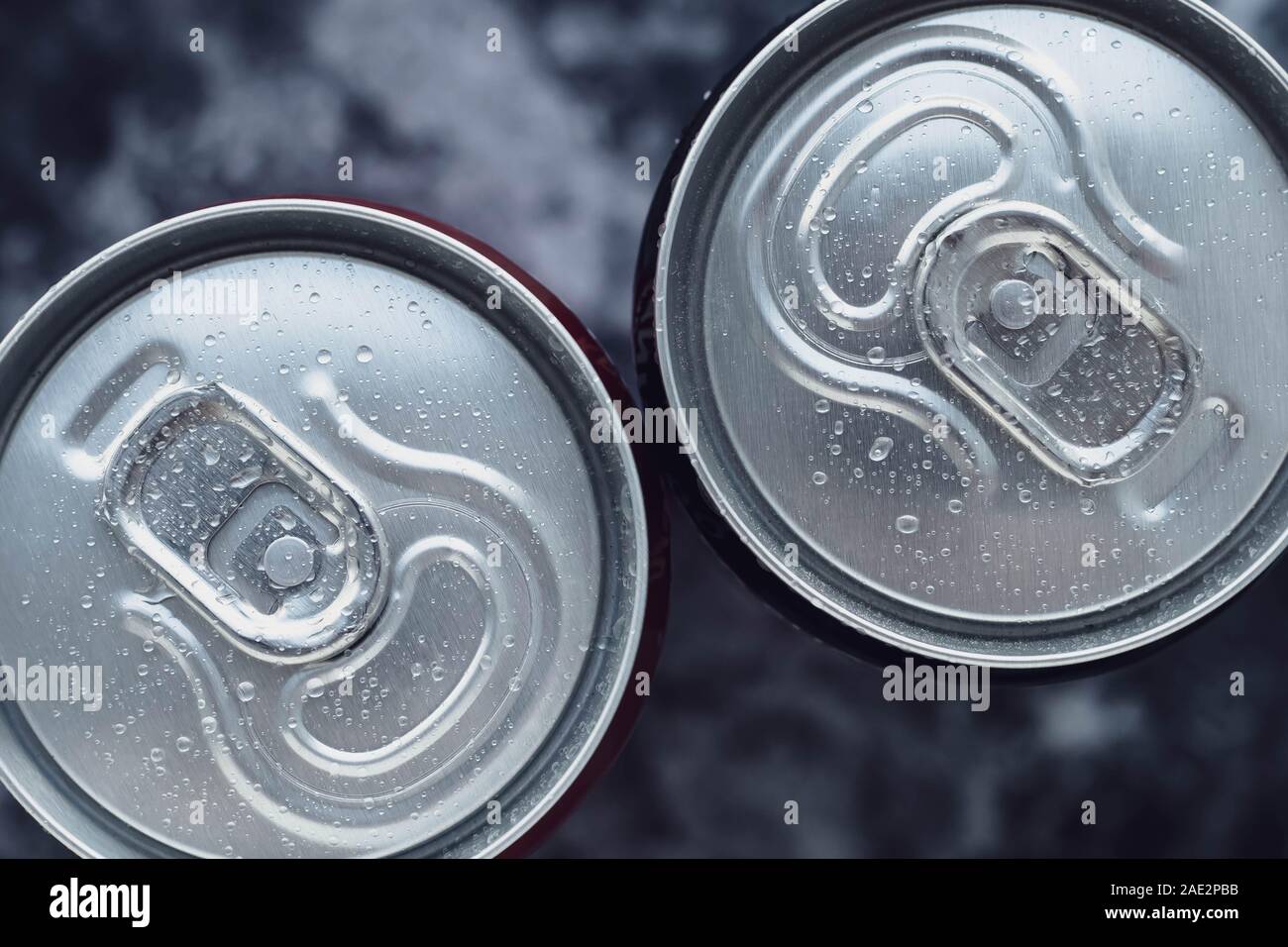 Cola Dosen auf dunklem Hintergrund. Ansicht von oben. Kondensat, Wassertropfen auf zwei Dosen mit einem Getränk. Stockfoto