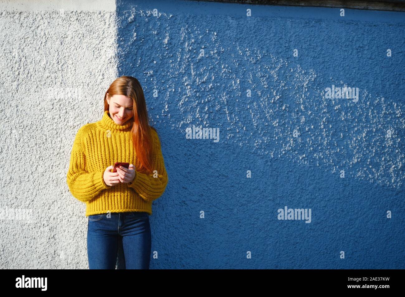 Junge rothaarige Frau Sms mit Telefon im Freien Stockfoto