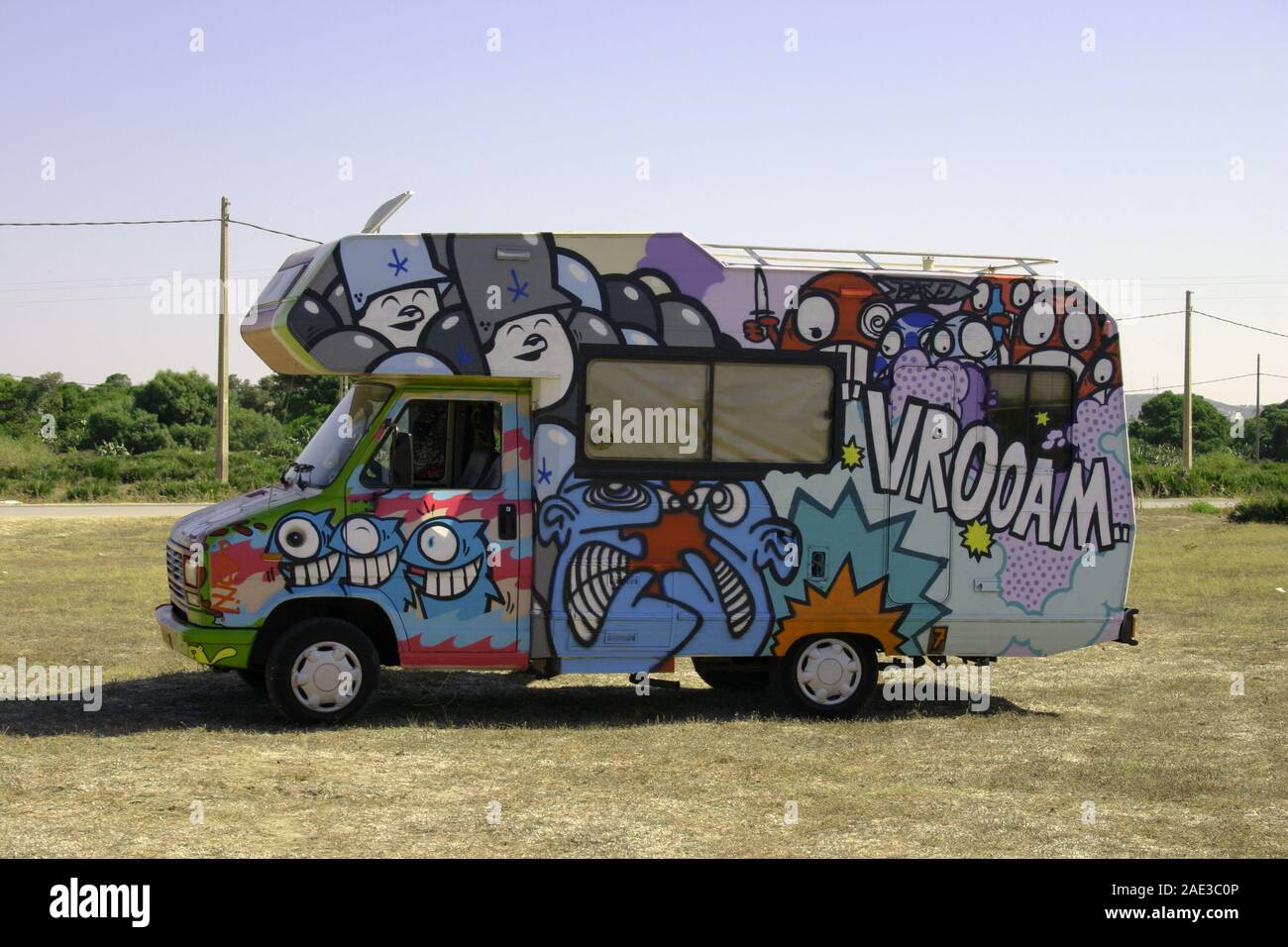 Bizarre und bunte Kunstwerke decken einen ausharrenden Lieferwagen ab, der allein auf einem Feld unter blauem Himmel steht, El Palmar, Cadiz, Andalusien, Spanien Stockfoto