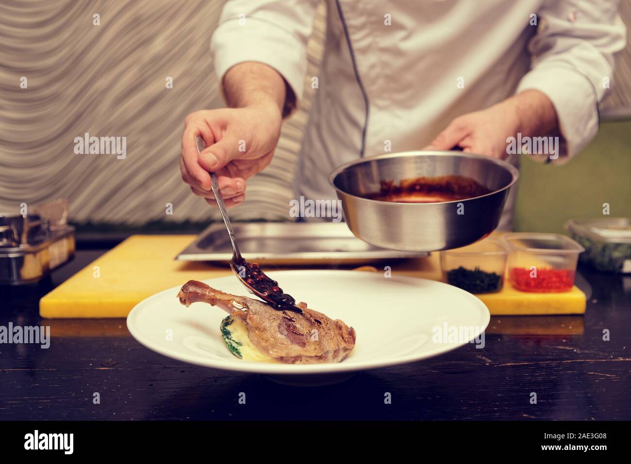 Koch ist Gießen berry Soße über getrocknete Ente Bein, getönt, Rauschen hinzugefügt Stockfoto