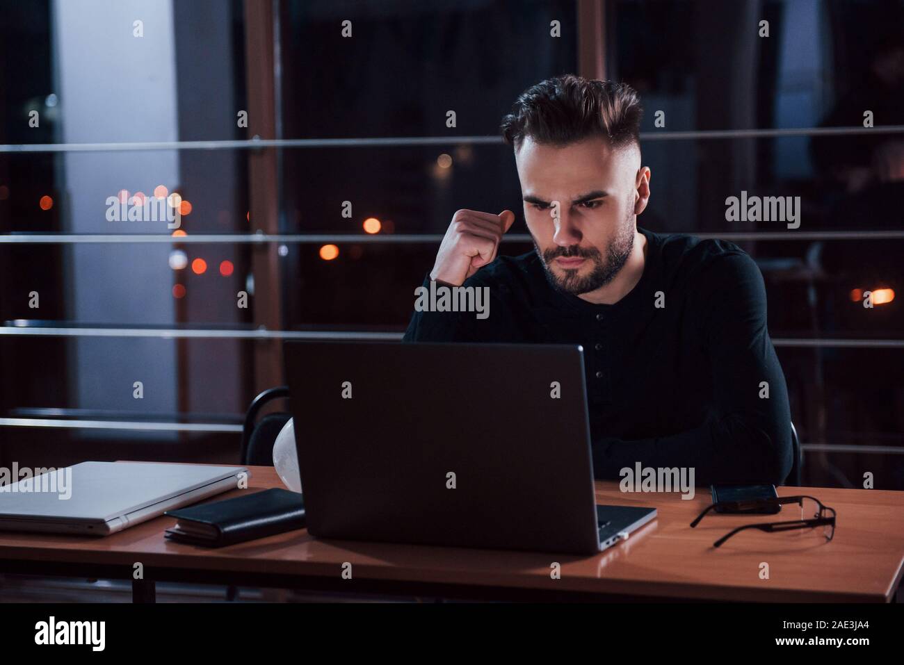 Müssen härter zu arbeiten. Stilvolle Junge Unternehmer sitzt alleine im Büro bei Nacht Stockfoto