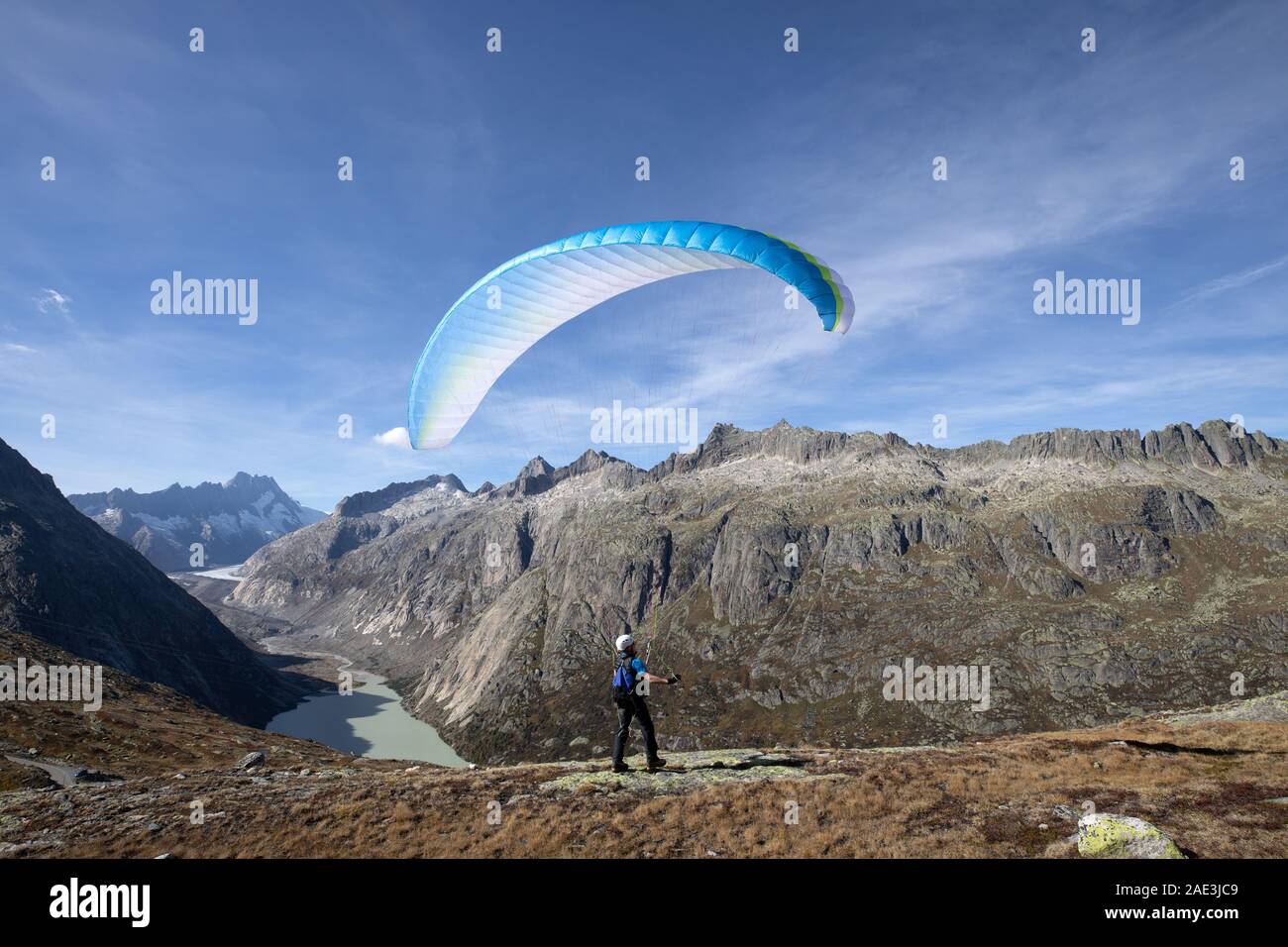 Gleitschirm Pilot steht auf einem Felsen und gleicht seinem Gleitschirm über seinem Kopf in der Nähe des Sees von Grimsel in den Schweizer Alpen Stockfoto