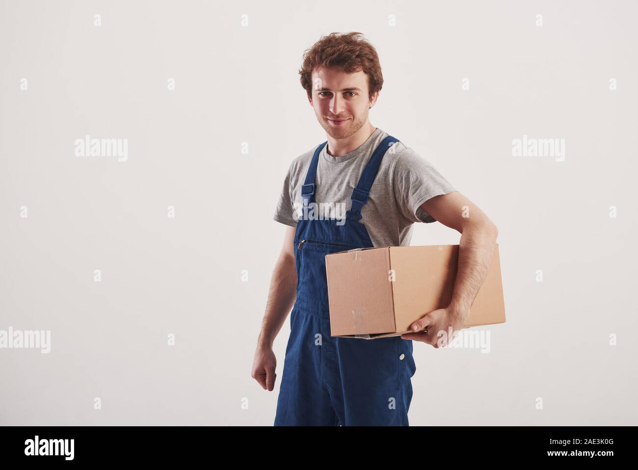 Kerl mit Box in den Händen steht vor weißem Hintergrund im Studio Stockfoto