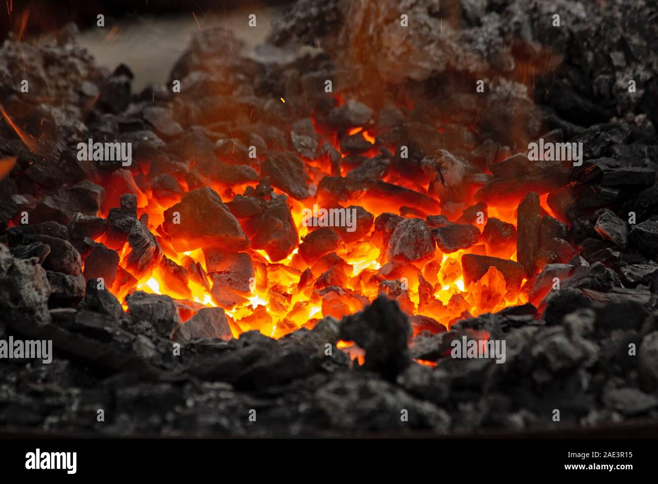 Flammen und Glut Leuchten in einem Lagerfeuer. Feuer, Hitze, Kohle und Asche mit Funkenflug. Stockfoto