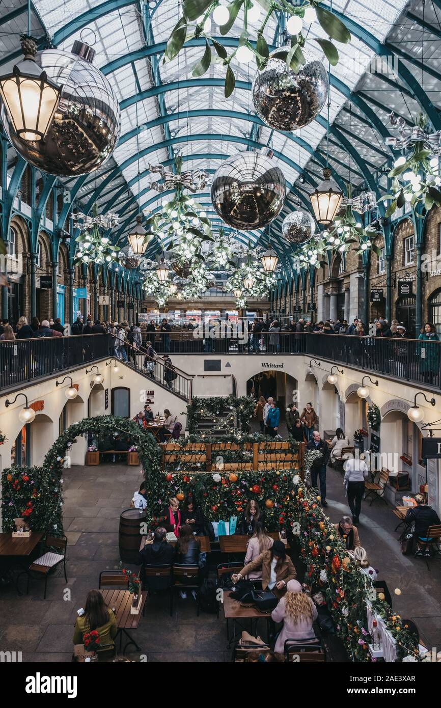 London, Großbritannien - 24 November, 2019: die Menschen sitzen unter Weihnachtsschmuck an Tischen im Außenbereich eines Cafés in Covent Garden Market, einer der am meisten Population Stockfoto