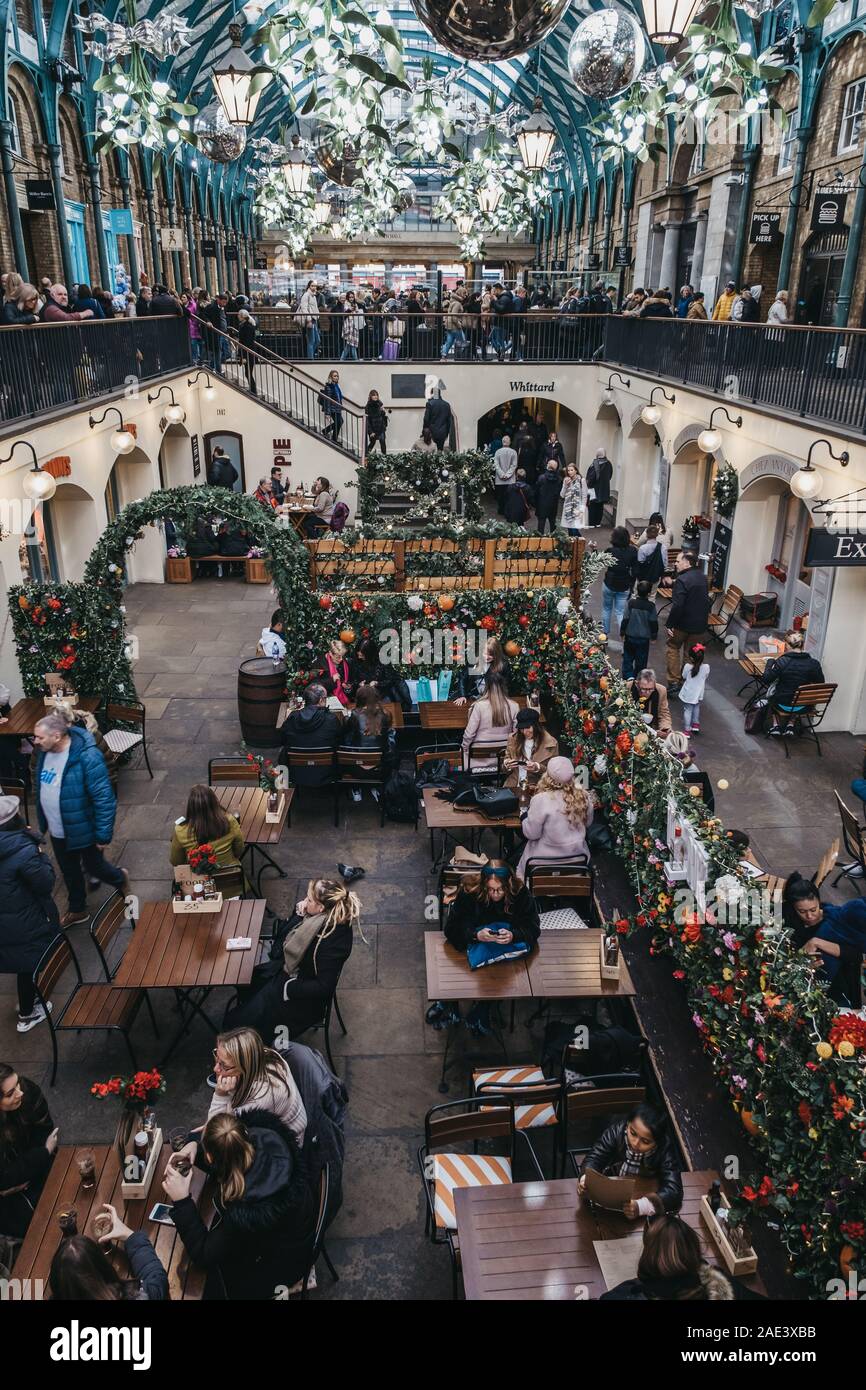 London, Großbritannien - 24 November, 2019: die Menschen sitzen unter Weihnachtsschmuck an Tischen im Außenbereich eines Cafés in Covent Garden Market, einer der am meisten Population Stockfoto