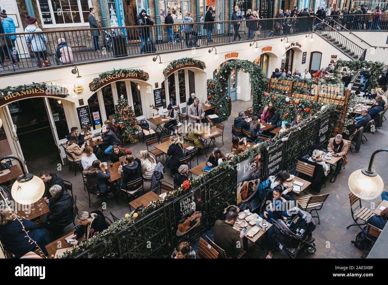 London, Großbritannien - 24 November, 2019: die Menschen sitzen unter Weihnachtsschmuck an Tischen im Außenbereich eines Cafés in Covent Garden Market, einer der am meisten Population Stockfoto