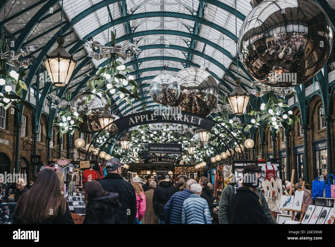 London, Großbritannien - 24 November, 2019: die Menschen gehen unter Apple Markt Zeichen und Weihnachtsschmuck und einer riesigen Kugeln in Covent Garden Market, einer der Stockfoto