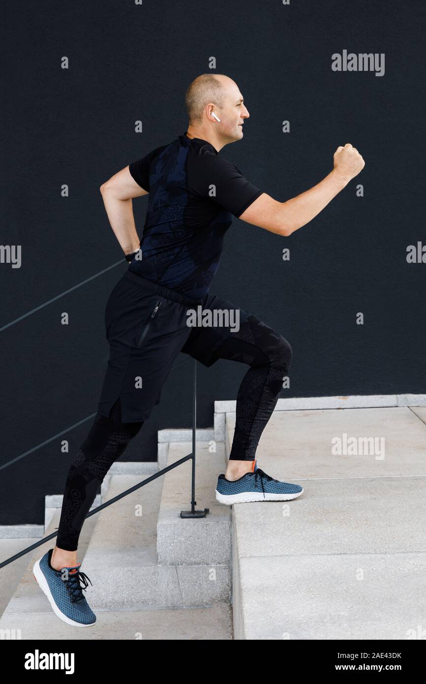 Junge hoch manly Mann ist aktiv im Sport auf der Straße gegen eine schwarze Wand Hintergrund Stockfoto