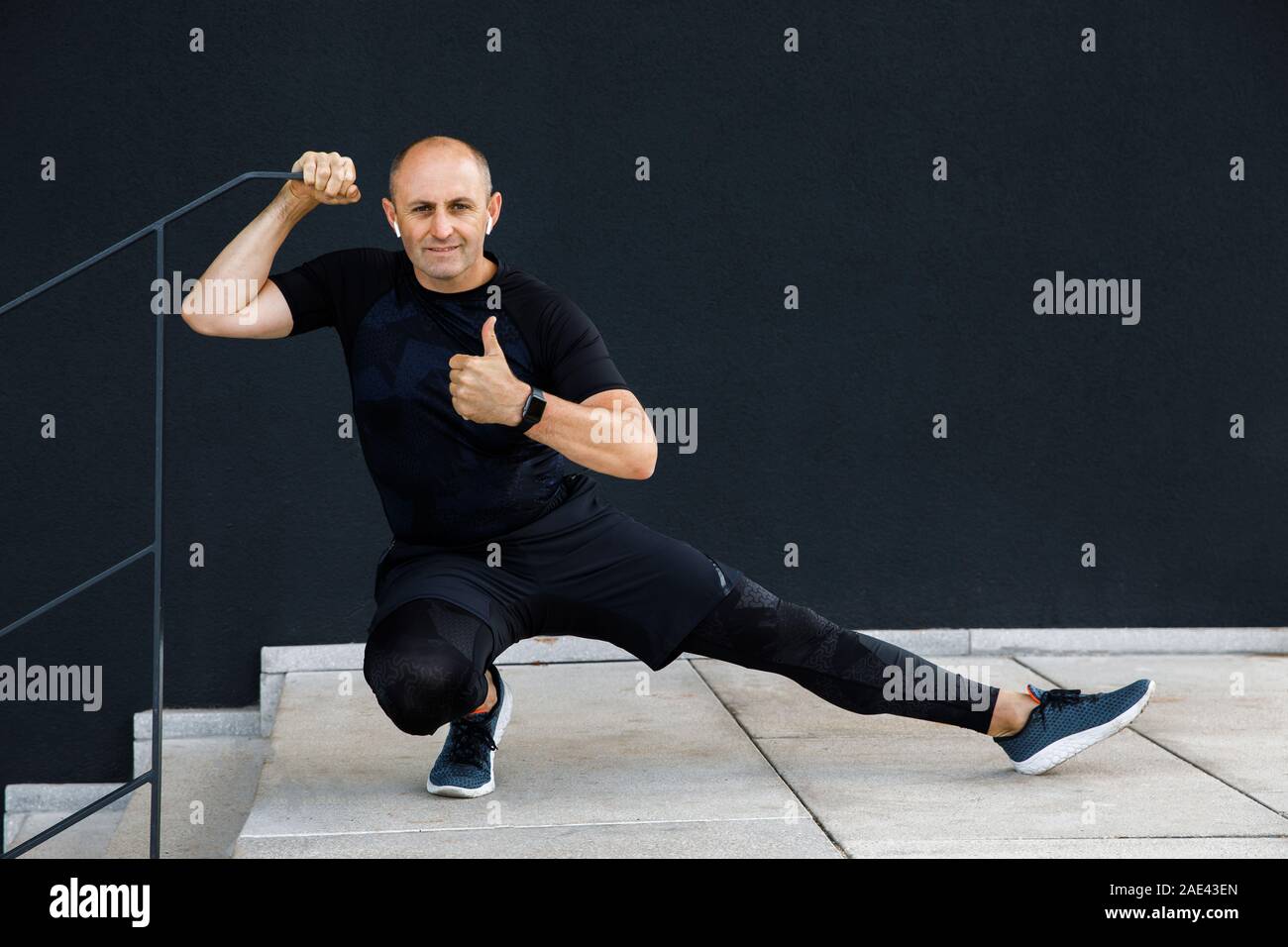 Junge hoch manly Mann ist aktiv im Sport auf der Straße gegen eine schwarze Wand Hintergrund Stockfoto