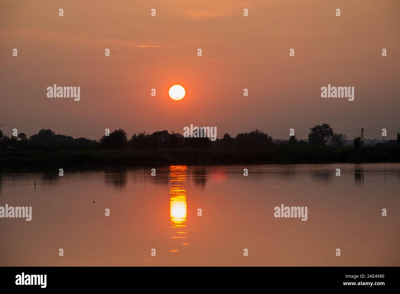 Roter Sonnenuntergang über einem ruhigen See - Reflexion der Sonne im Wasser Stockfoto