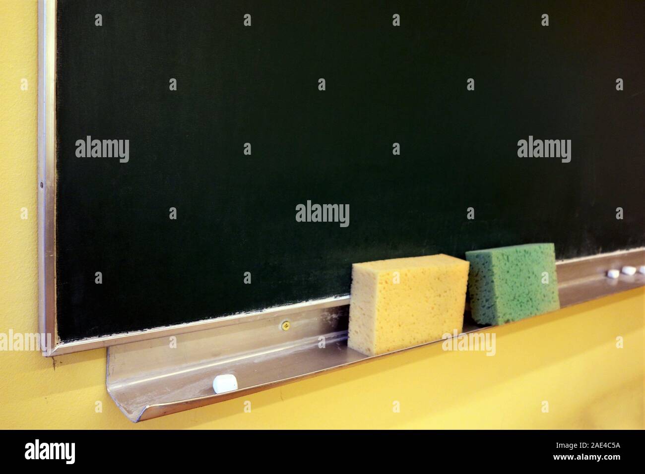 Kreide und Schwämme auf das Fach unter einem alten grünen Tafel Stockfoto