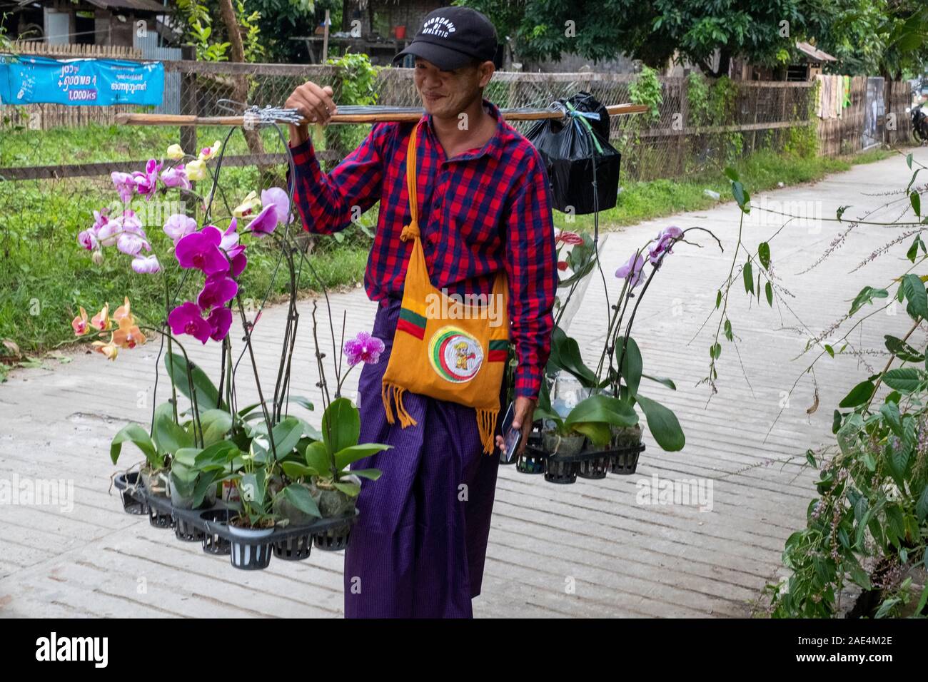 Nach Burma Mann in Baseball Cap mit einem mobilen Orchideen Garten mit Orchideen für den Verkauf in einem Dorf am Chindwin Fluss im Nordwesten Myanmar (Birma) Stockfoto