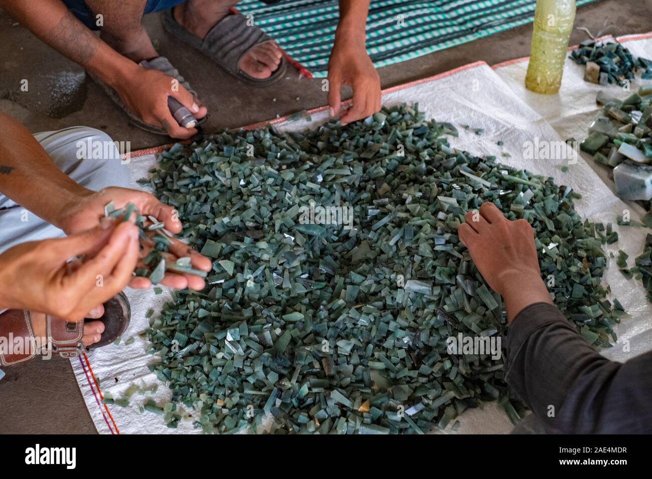 Die Hände und Taschenlampen von zahlreichen Kunden beurteilen die Qualität der Jade Steine in der Jade Markt von Mandalay, Myanmar (Birma) Stockfoto