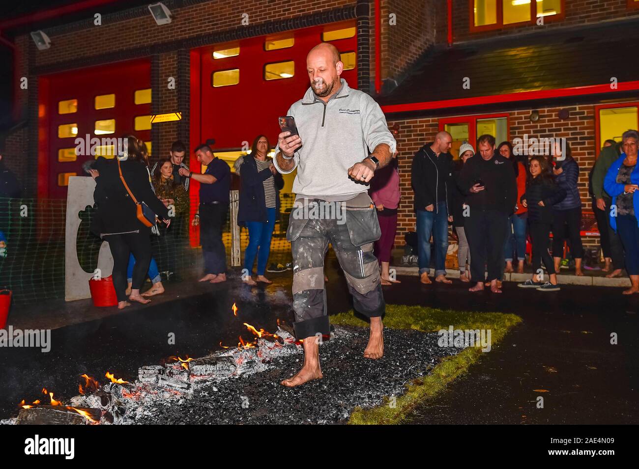 Bridport, Dorset, Großbritannien. 6. Dezember 2019. Mitglieder der öffentlichkeit gehen über glühende Kohlen, wie Sie an eine Wohltätigkeitsorganisation firewalk bei Bridport Gemeinschaft Feuerwache in Dorset zugunsten der Feuerwehrleute Charity. Foto: Graham Jagd-/Alamy Leben Nachrichten. Stockfoto