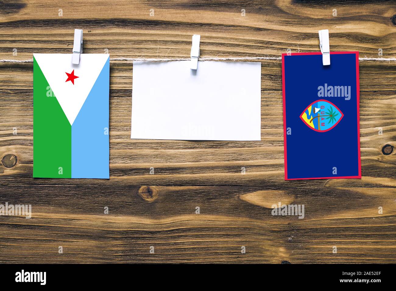 Hängenden Flaggen von Dschibuti und Guam Seil mit wäscheklammer mit Kopie Raum befestigt auf weißem Papier auf Holz- Hintergrund. Diplomatische Beziehungen. Stockfoto
