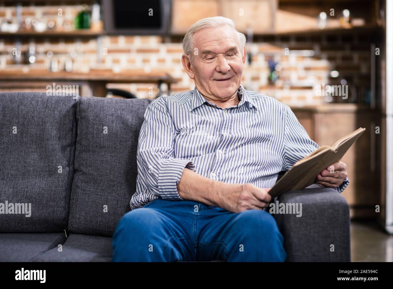 Freudige älterer Mann Lesung mit Vergnügen Stockfoto