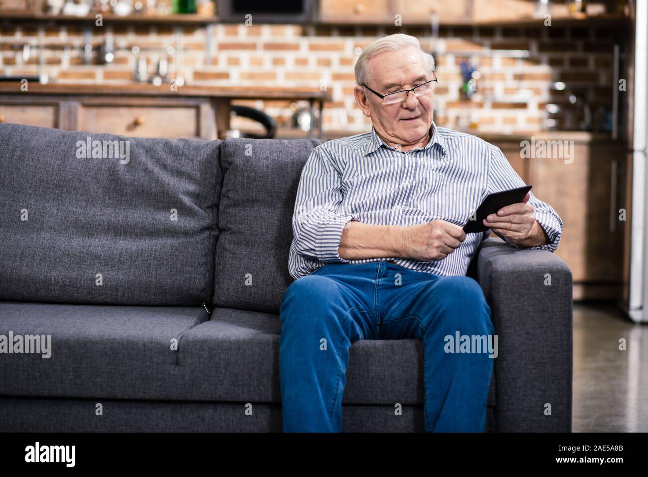 Positive älterer Mann lesen Ein e-Buch Stockfoto