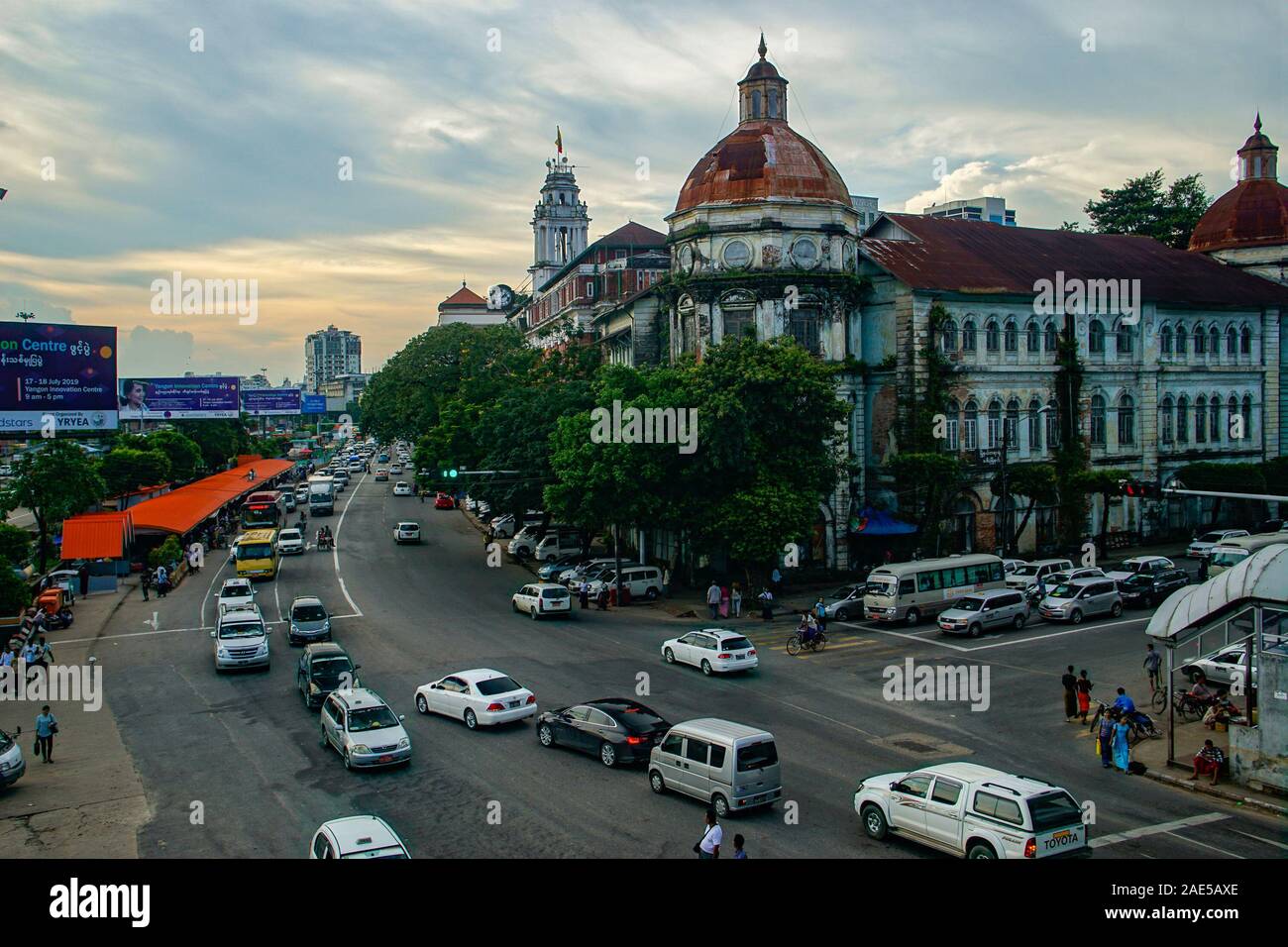 Blick über den belebten Kreuzung der Pansodan St und Strand Rd in Yangon (früher Rangoon), Myanmar (Burma) in der Dämmerung mit Verkehr und verfallenden Kolonialbauten Stockfoto