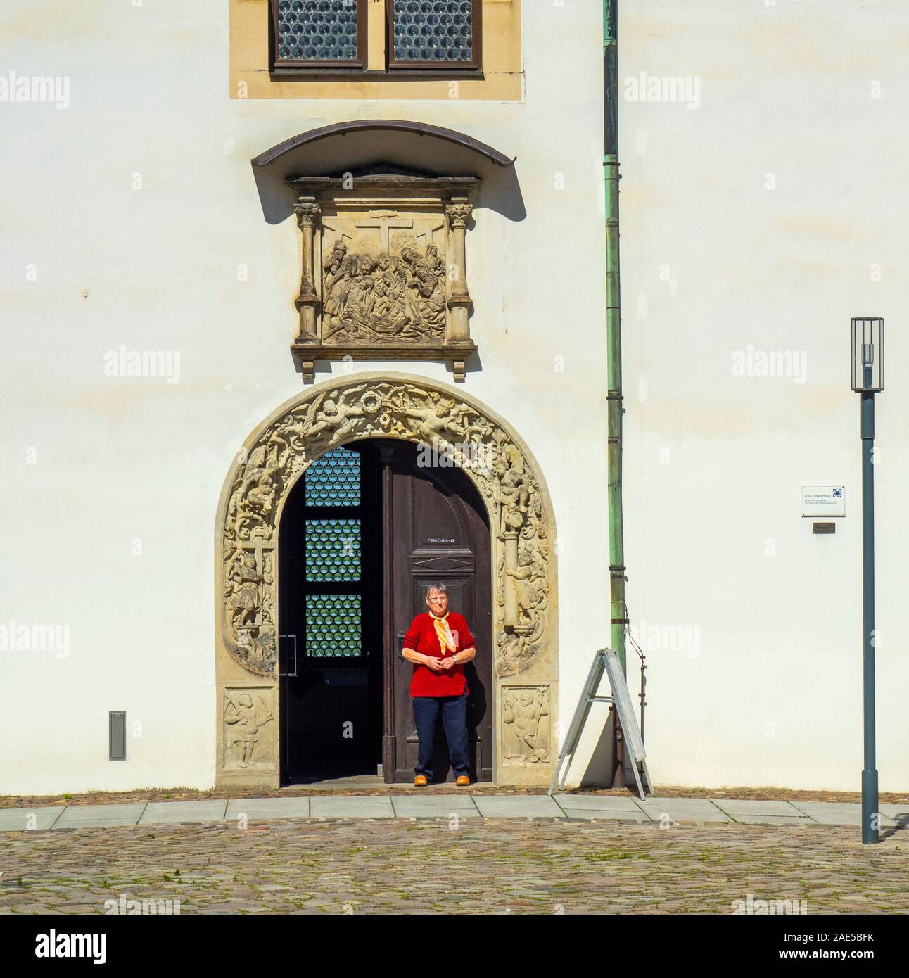 Kaukasische Frau steht im Portal zur Burg Hartenfels Kapelle die erste evangelische Kirche der Welt Altstadt Torgau Sachsen Deutschland. Stockfoto