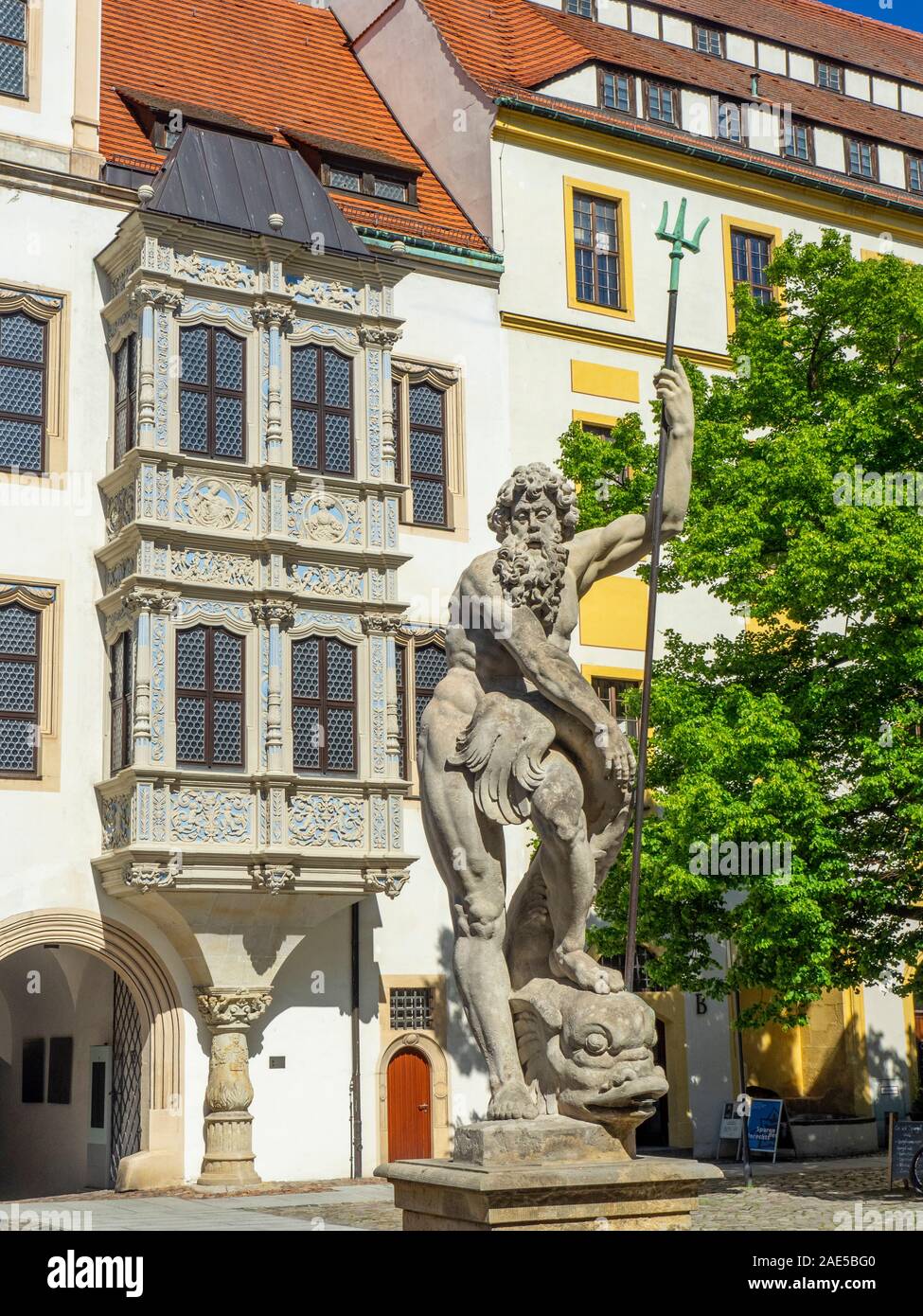 Steinstatue des Neptun im Brunnen und schöner Erkerin Erkerbucht Fensterhof von Schloss Hartenfels Altstadt Torgau Sachsen Deutschland. Stockfoto