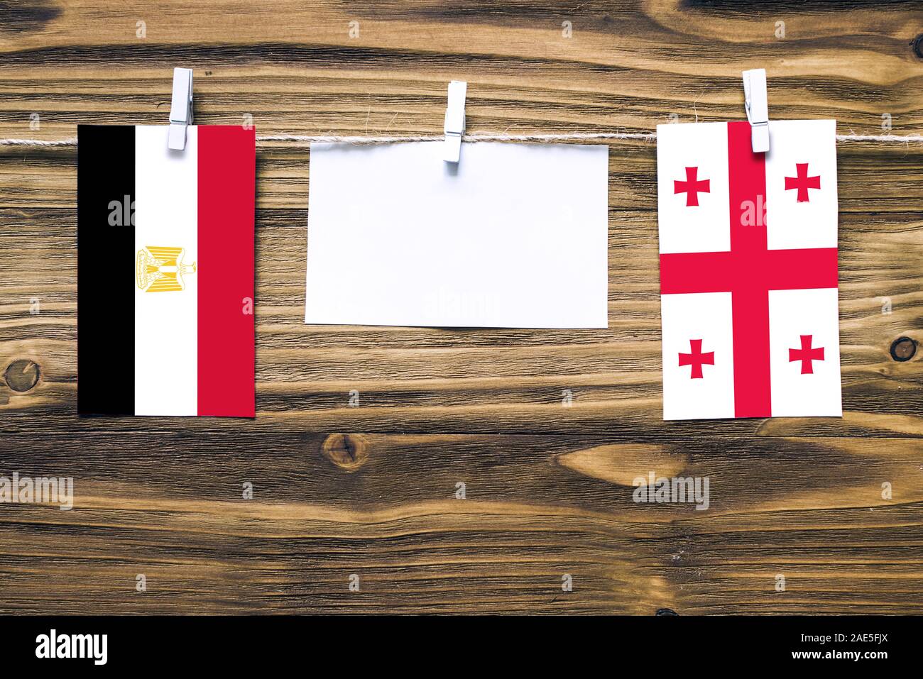 Hängenden Flaggen von Ägypten und Georgien zu Seil mit wäscheklammer mit Kopie Raum befestigt auf weißem Papier auf Holz- Hintergrund. Diplomatische Beziehungen. Stockfoto